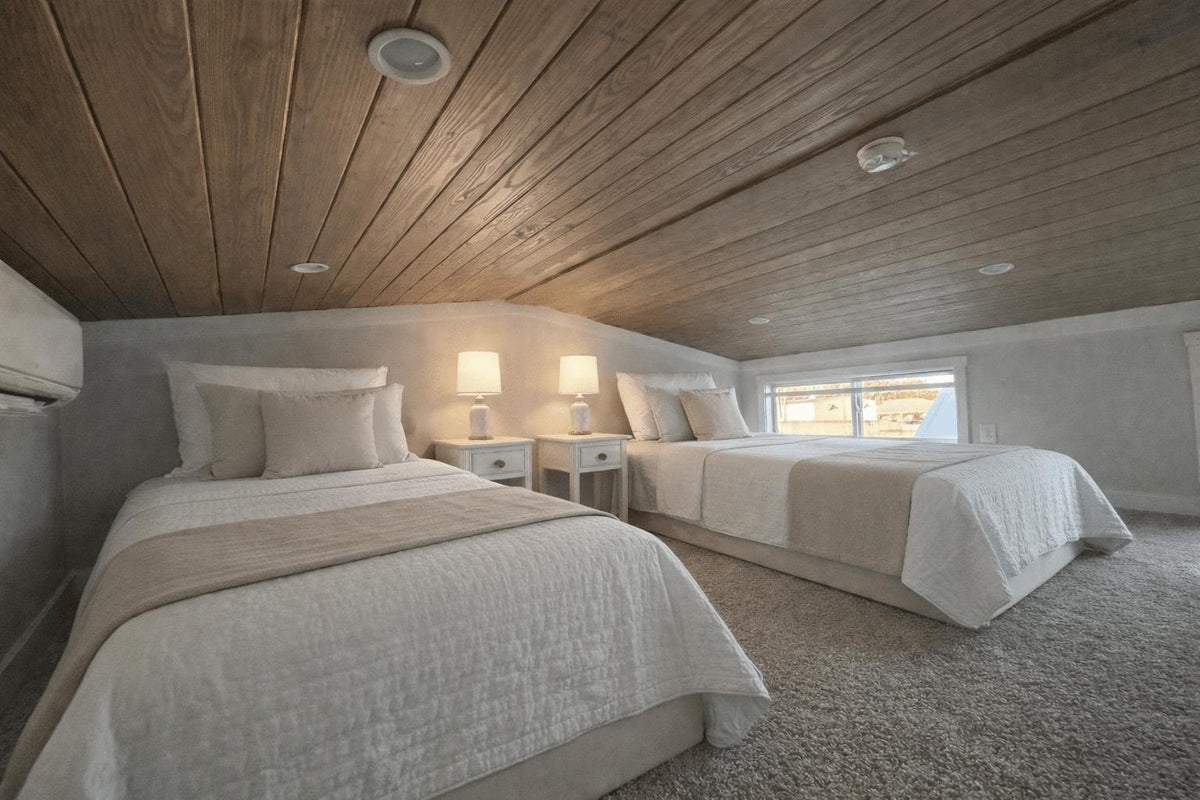 Kids' loft at Honey Hollow with two single beds under a low wood ceiling